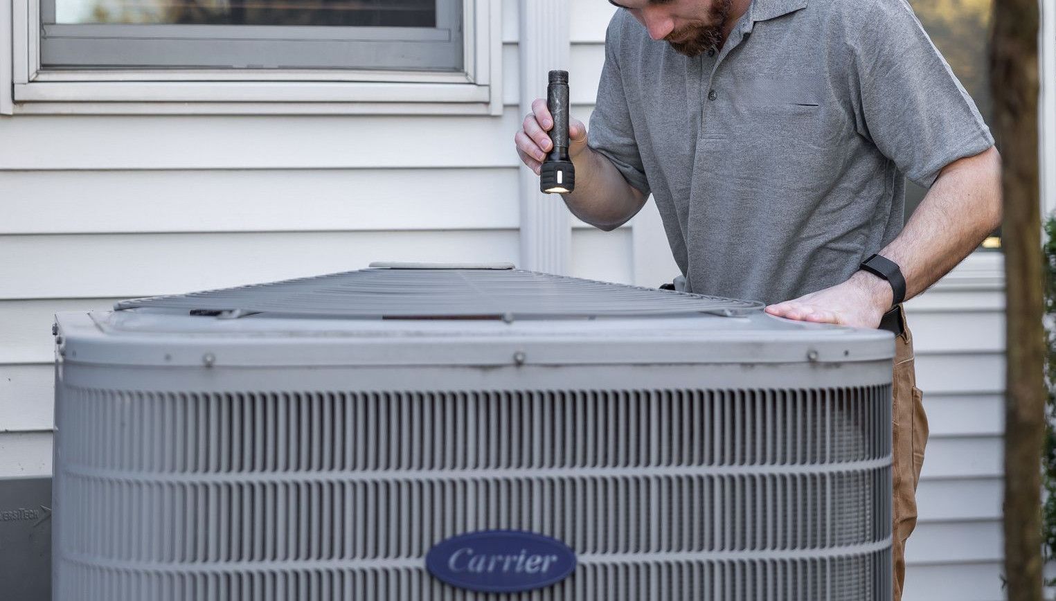 A technician inspects an outdoor HVAC unit for maintenance.